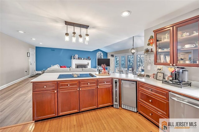 kitchen featuring stainless steel appliances, light countertops, open floor plan, and decorative light fixtures