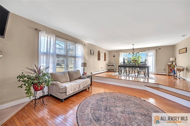 living area with baseboard heating, a baseboard radiator, baseboards, and wood finished floors