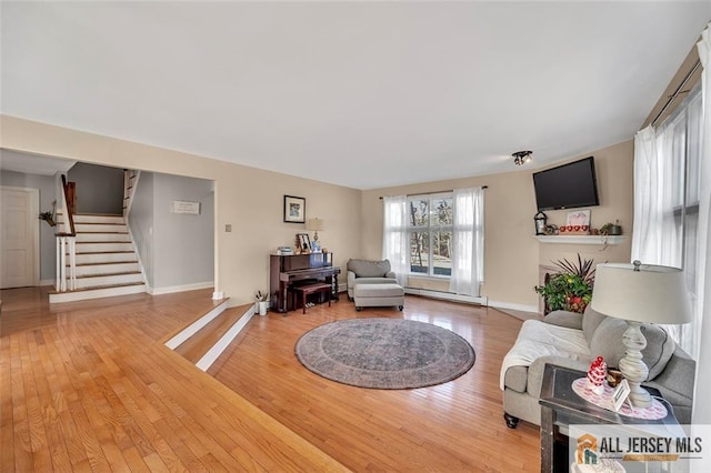 living room with a baseboard radiator, stairs, baseboards, and wood finished floors