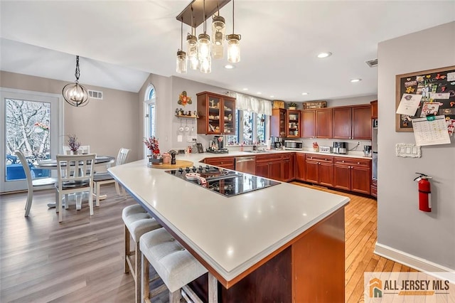 kitchen with a peninsula, light countertops, appliances with stainless steel finishes, glass insert cabinets, and an inviting chandelier