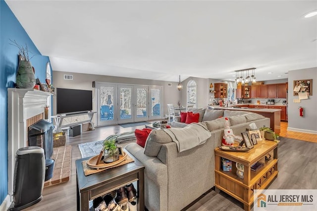 living room featuring a chandelier, visible vents, a fireplace, and light wood-style flooring