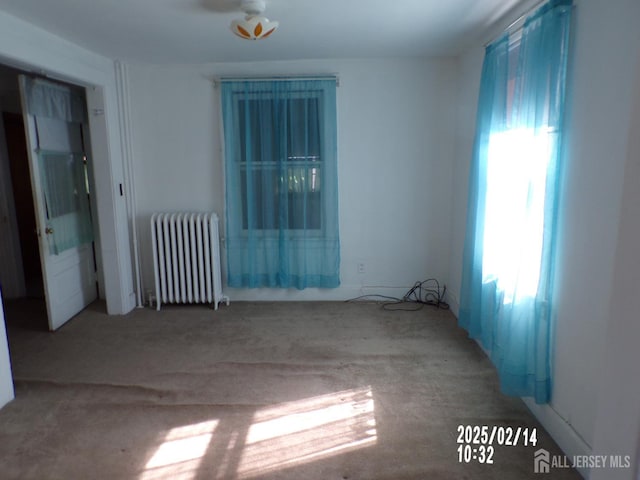 empty room featuring light carpet and radiator