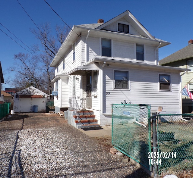 american foursquare style home with driveway, a chimney, and fence