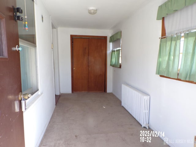 hallway featuring light carpet and radiator heating unit