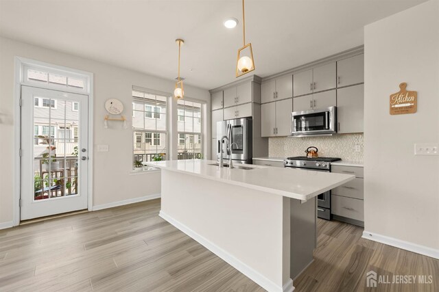 4 Arnold Dr Unit 5302, Wood-Ridge, NJ 07075 - kitchen with stainless steel appliances, gray cabinets, light countertops, decorative backsplash, and light wood-style floors