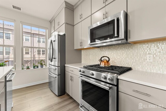 4 Arnold Dr Unit 5302, Wood-Ridge, NJ 07075 - kitchen featuring stainless steel appliances, light countertops, light wood-style floors, backsplash, and gray cabinetry