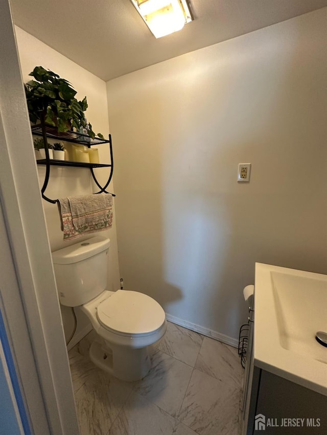 bathroom with toilet, marble finish floor, baseboards, and vanity