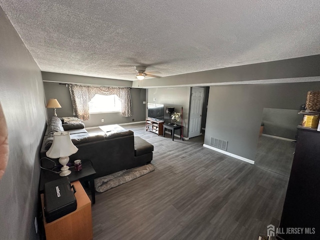 living room with visible vents, a ceiling fan, a textured ceiling, wood finished floors, and baseboards