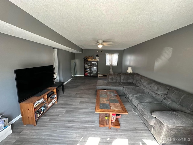 living room with baseboard heating, ceiling fan, a textured ceiling, wood finished floors, and baseboards