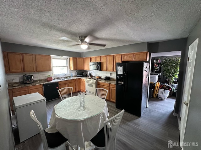 kitchen with decorative backsplash, dark wood finished floors, brown cabinets, black appliances, and a sink