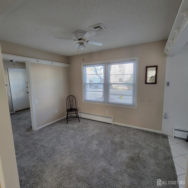 spare room featuring light carpet, a baseboard radiator, a textured ceiling, and ceiling fan