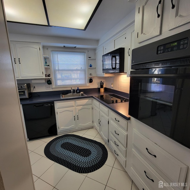 kitchen with black appliances, light tile patterned floors, white cabinets, backsplash, and sink