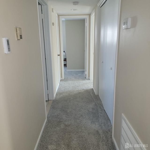 corridor featuring baseboards and light colored carpet