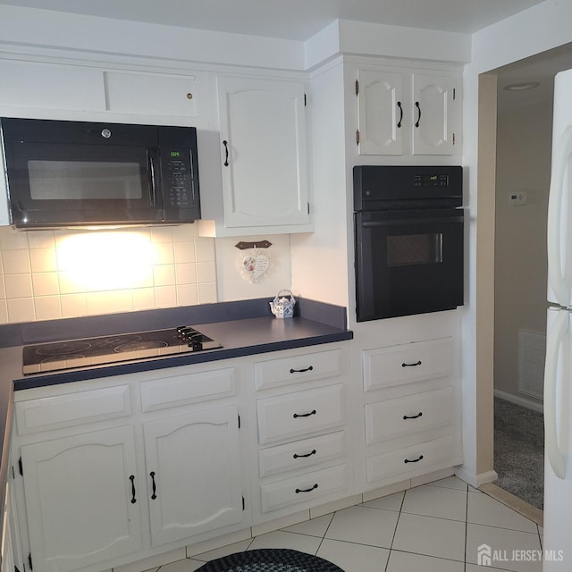 kitchen with light tile patterned floors, white cabinets, decorative backsplash, black appliances, and dark countertops