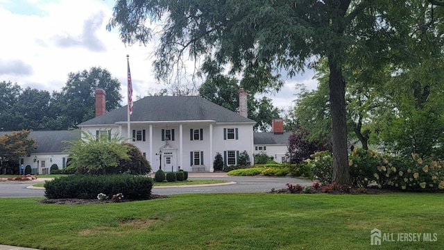 view of front of house featuring a front yard, a chimney, and stucco siding