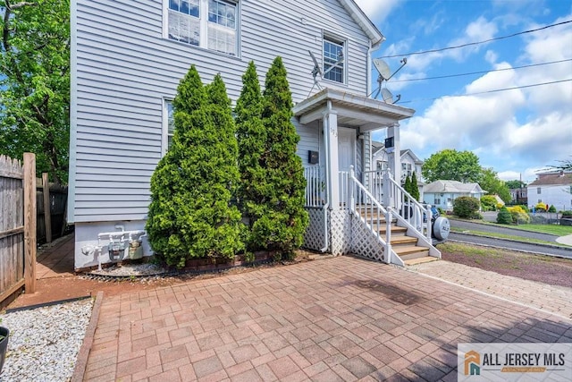 entrance to property featuring fence and a patio area