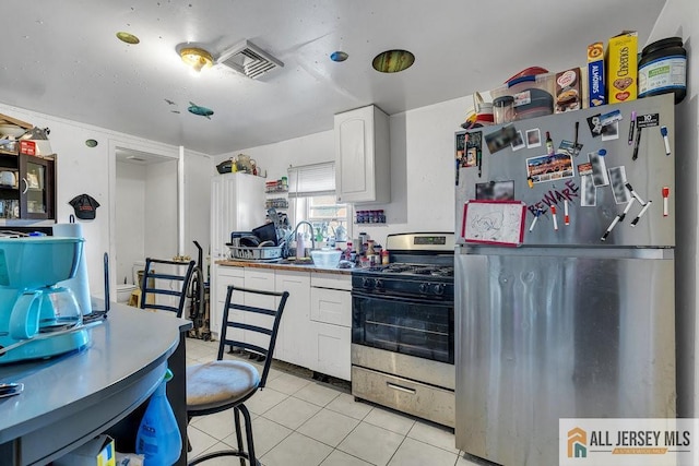 kitchen featuring stainless steel appliances, white cabinetry, light tile patterned floors, and a sink