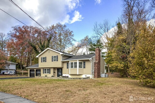 view of front of property with central AC and a front lawn