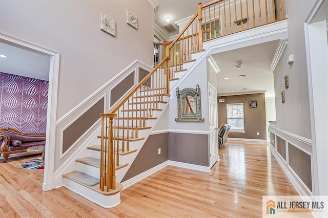 staircase featuring hardwood / wood-style flooring, ornamental molding, and a high ceiling