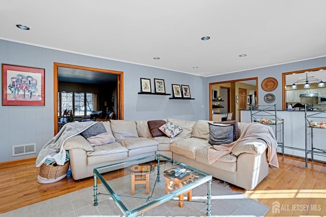 living area with light wood finished floors, recessed lighting, visible vents, a baseboard heating unit, and ornamental molding