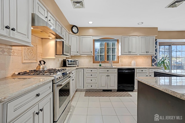 kitchen with stainless steel appliances, light stone countertops, visible vents, and white cabinets