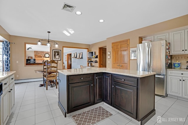 kitchen with visible vents, dark brown cabinets, freestanding refrigerator, and a center island