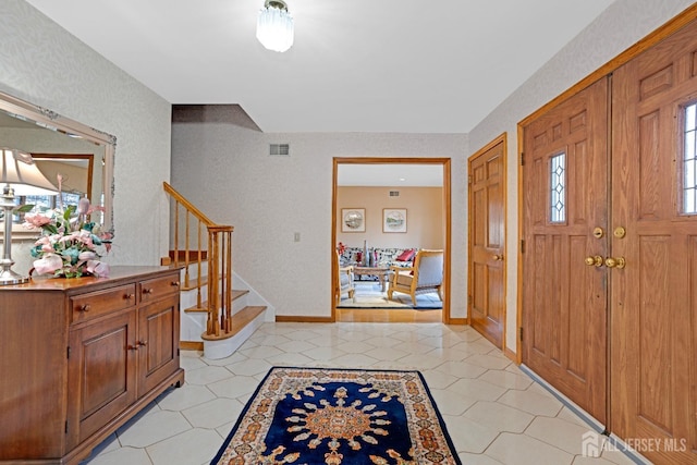 entryway with stairs, light tile patterned floors, visible vents, and baseboards