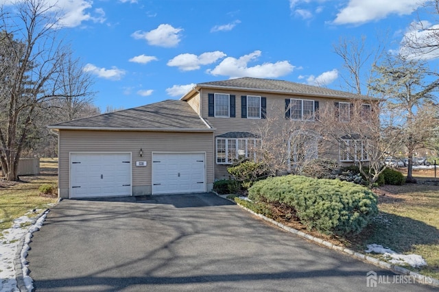 colonial house with an attached garage and aphalt driveway