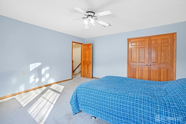 bedroom with ceiling fan, baseboards, a closet, and light colored carpet