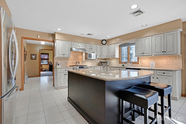 kitchen featuring light tile patterned flooring, white cabinetry, stainless steel appliances, and a center island