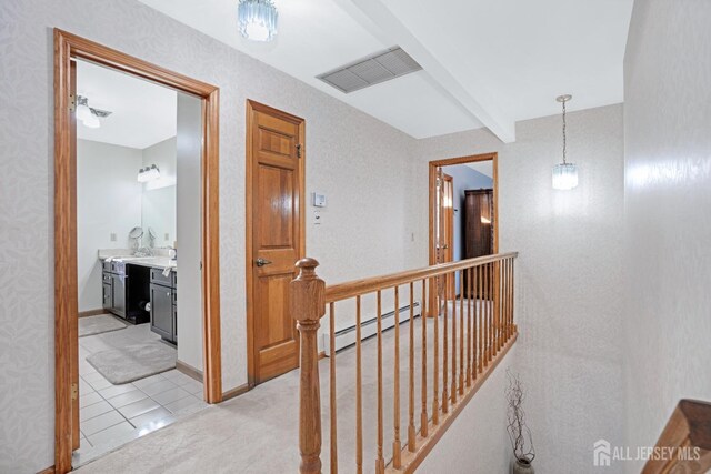 hall featuring light tile patterned floors, an upstairs landing, visible vents, baseboard heating, and beam ceiling