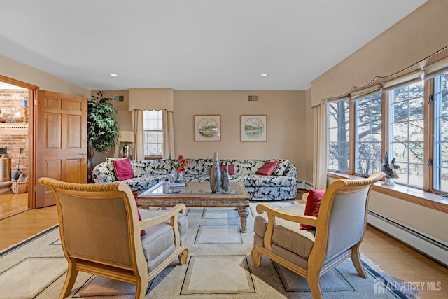 living area with a baseboard radiator, visible vents, and light wood-style floors