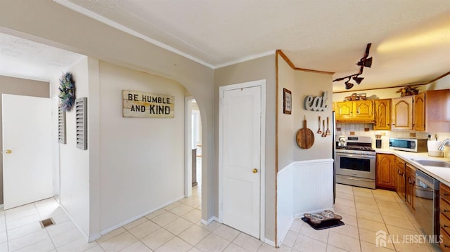 68 Applegate Ave, Monroe, NJ 08831 - kitchen featuring stainless steel range with gas stovetop, a sink, light countertops, arched walkways, and brown cabinets