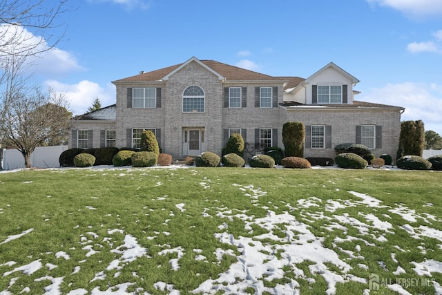 view of front of property with brick siding, a front yard, and fence