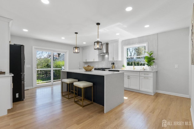 39 S Pierson Rd, Maplewood, NJ 07040 - kitchen with freestanding refrigerator, wall chimney range hood, a center island, light countertops, and white cabinets