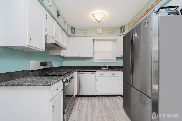 kitchen with sink, white cabinetry, light hardwood / wood-style flooring, stainless steel appliances, and dark stone counters