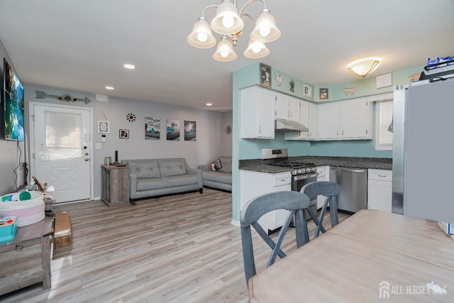 kitchen featuring an inviting chandelier, white cabinetry, light hardwood / wood-style floors, stainless steel appliances, and pendant lighting