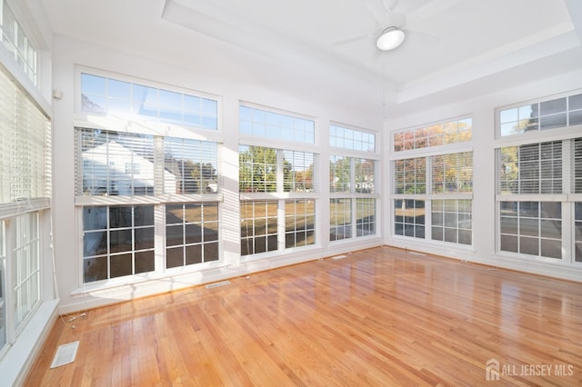 unfurnished sunroom with a tray ceiling, a ceiling fan, and visible vents