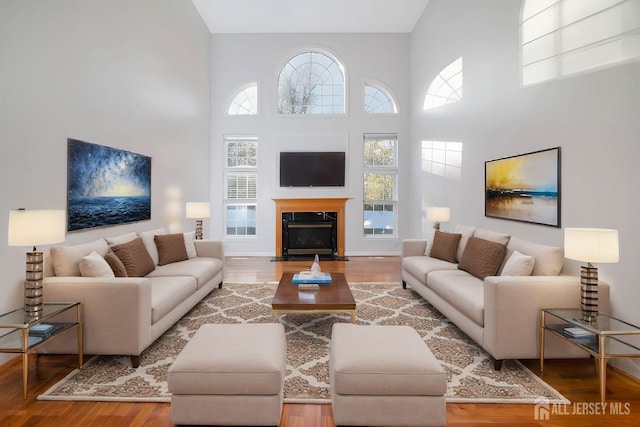 living area featuring a high end fireplace, a high ceiling, and wood finished floors