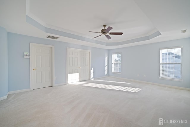 empty room featuring visible vents, a raised ceiling, baseboards, and carpet flooring