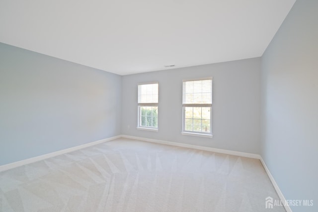 spare room with visible vents, light colored carpet, and baseboards