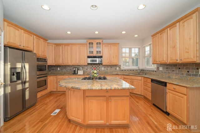 kitchen featuring a sink, appliances with stainless steel finishes, a center island, and light brown cabinetry