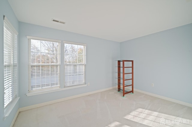 carpeted spare room featuring visible vents and baseboards