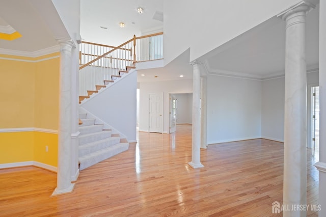 entryway featuring decorative columns, wood finished floors, baseboards, and ornamental molding