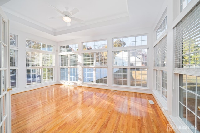 unfurnished sunroom featuring a wealth of natural light, a ceiling fan, and a tray ceiling