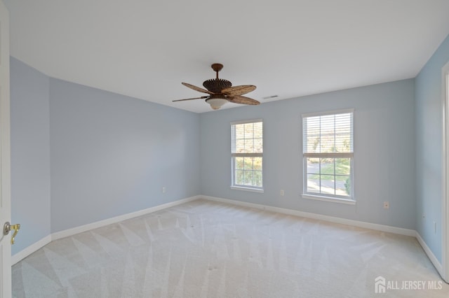 spare room with visible vents, baseboards, light colored carpet, and ceiling fan