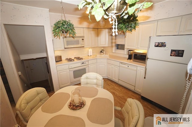 kitchen featuring wood-type flooring, sink, white cabinetry, white appliances, and backsplash