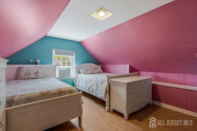 bedroom featuring cooling unit, vaulted ceiling, and light wood-type flooring