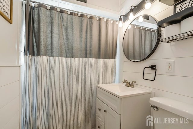 bathroom featuring tile walls, vanity, toilet, and curtained shower