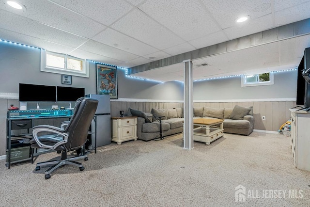 carpeted office with visible vents, a drop ceiling, and a wainscoted wall